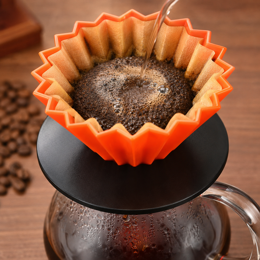 Dripper naranja con filtro y café molido sobre servidor de vidrio