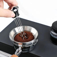 Mezclador de café espresso de acero inoxidable junto a una taza de espresso recién preparado, mejorando la calidad de la extracción y el sabor del café.